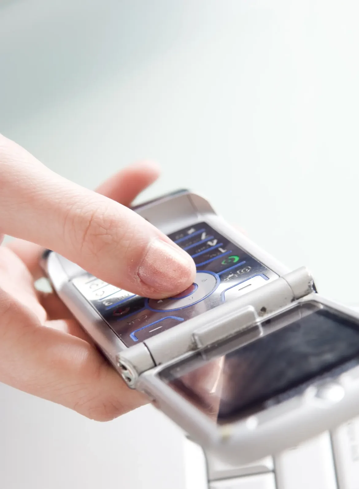 Finger pressing button on an open flip phone
