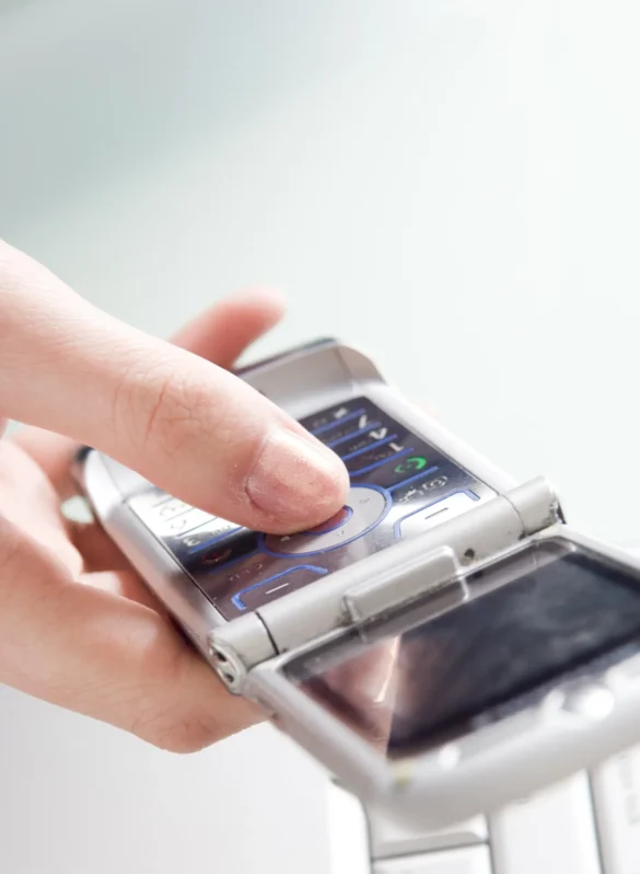 Finger pressing button on an open flip phone