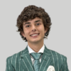 Young man in green pinstripe suit and patterned tie smiles warmly.