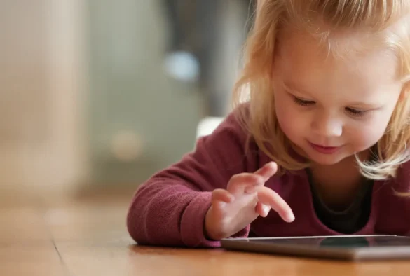 Blond toddler plays on a tablet computer.