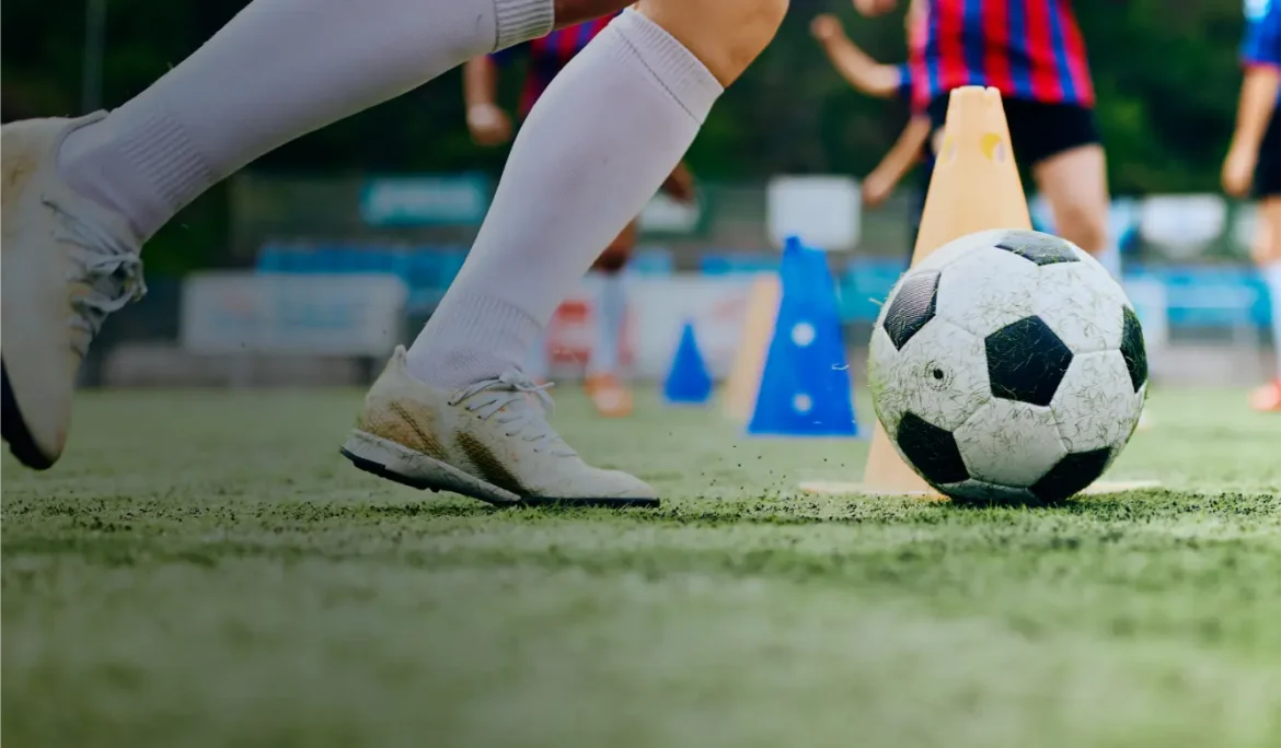 Soccer player's feet near a ball and cones during training practice