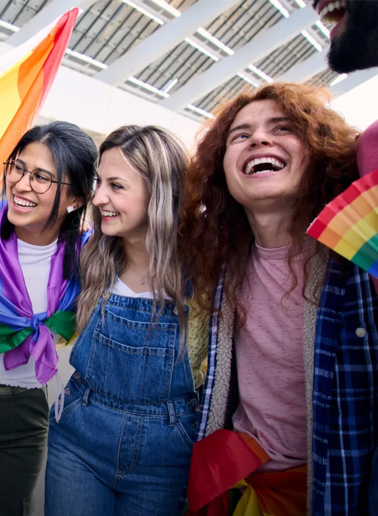 Diverse group of friends laughing at pride event with rainbow flags