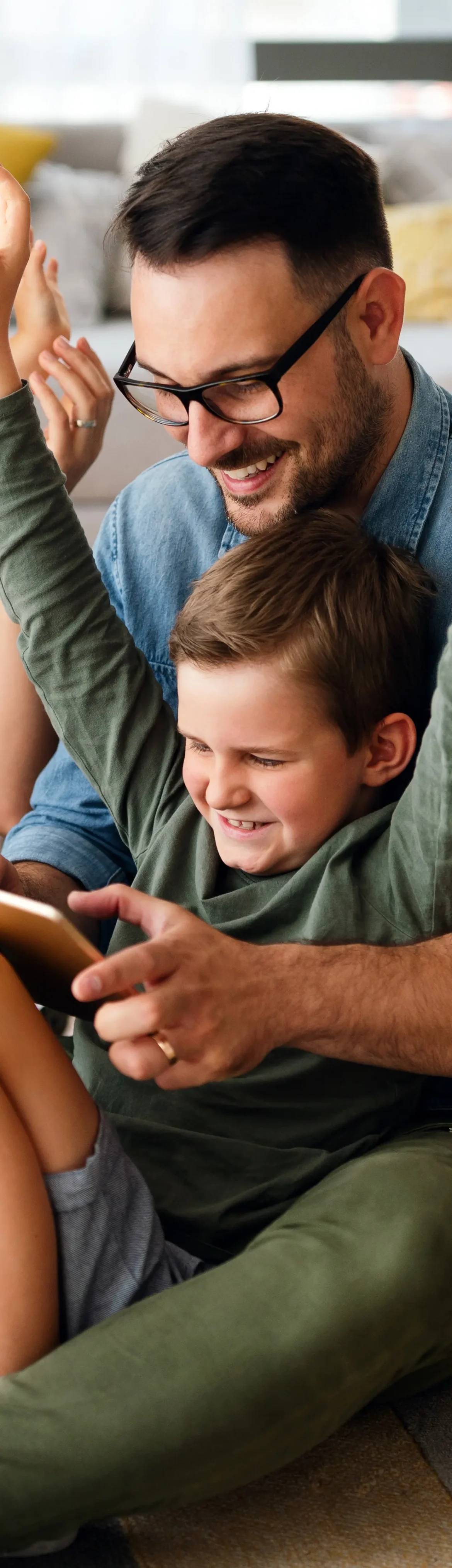 Father and son playing a game on a tablet together indoors.