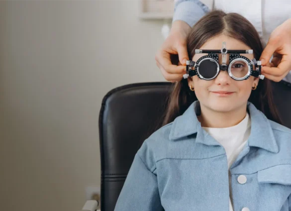 Child with trial frame for eye exam at optometry clinic.